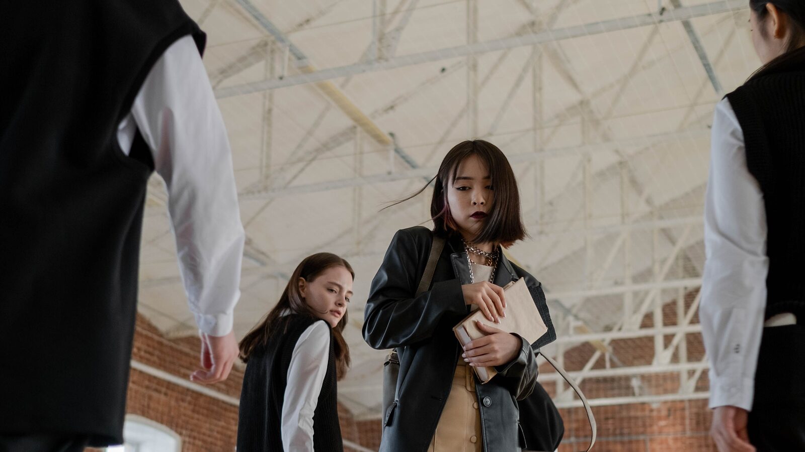 Students carrying books and folders as they walk through a school hall between lessons