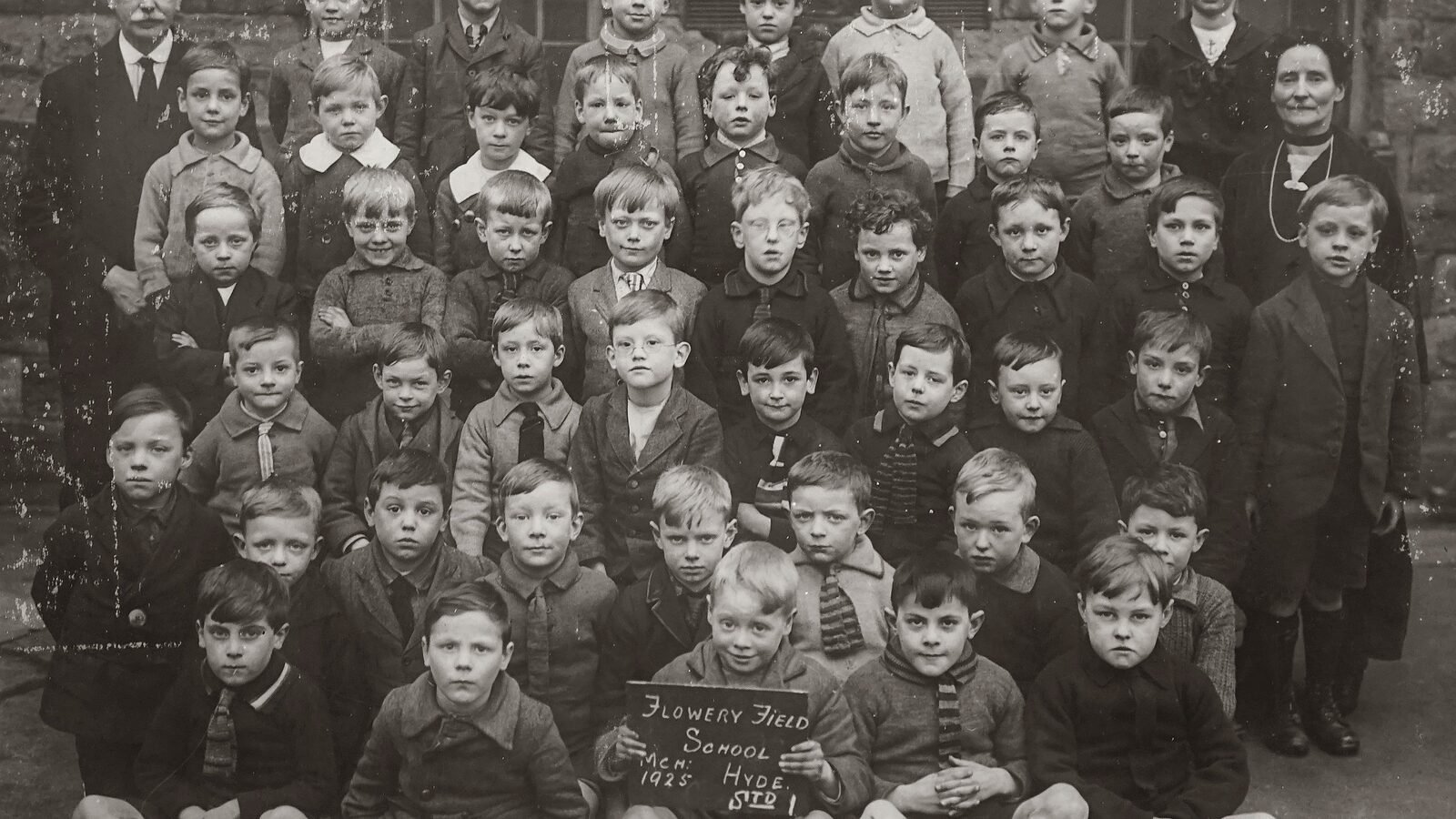 A black and white school class photograph from 1922, pupils posed in rows behind a slate naming the school and the year