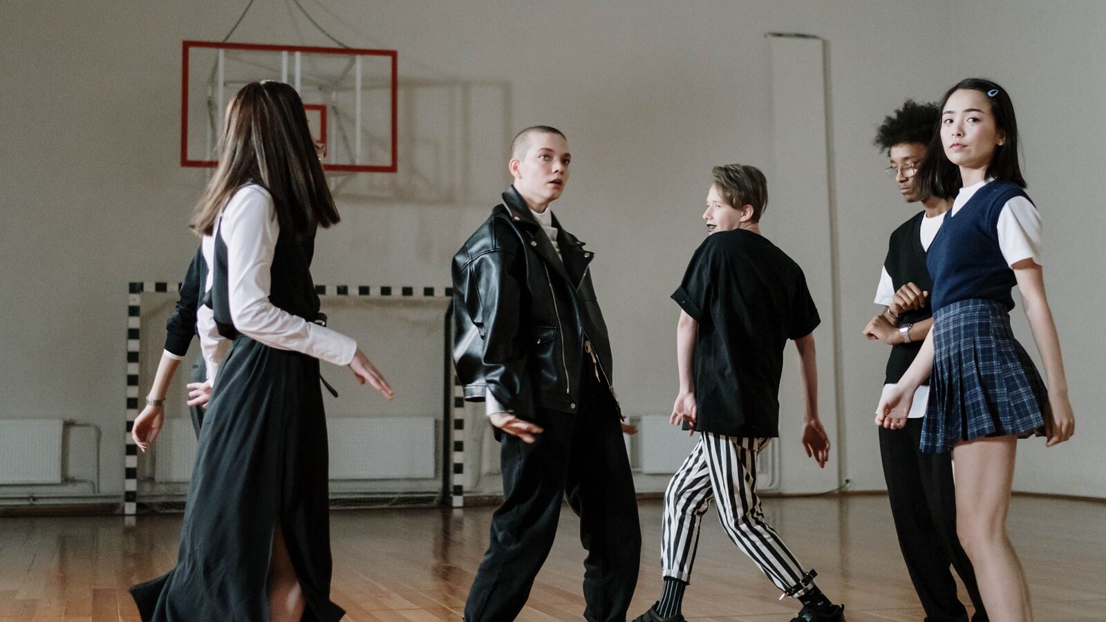 Students in school uniform walking across a sports hall marked out with court lines